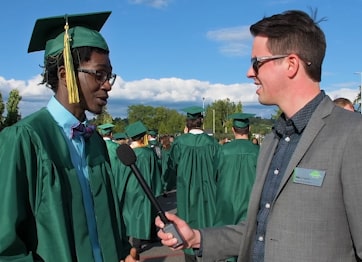 Phil Denman from College Relations interviewing a student before the 2018 commencement ceremony.