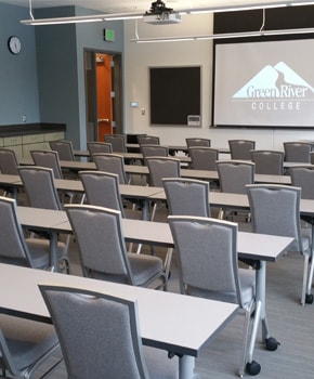 photo of Green River College's Pine Nobel classroom with tables, chairs, and a projector screen