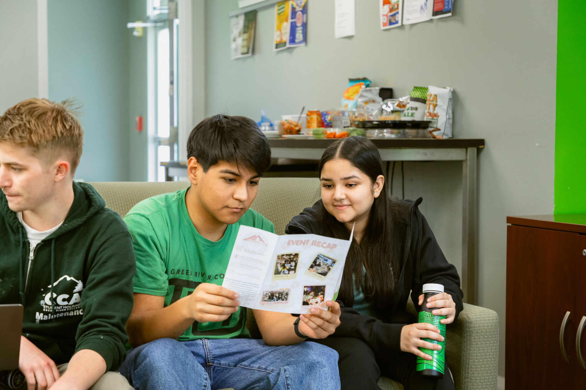 Students siting on a couch, reading a pamphlet