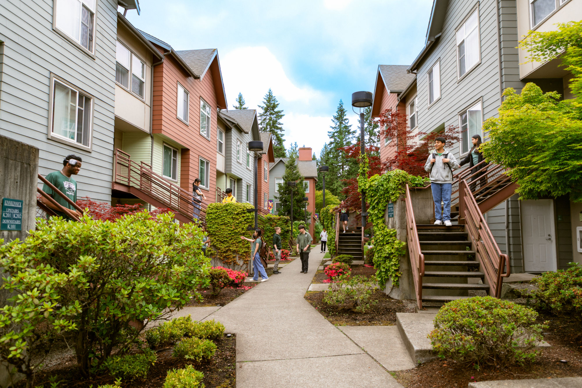 People on the stairs and walking along the sidewalk of the Campus Corner Apartments