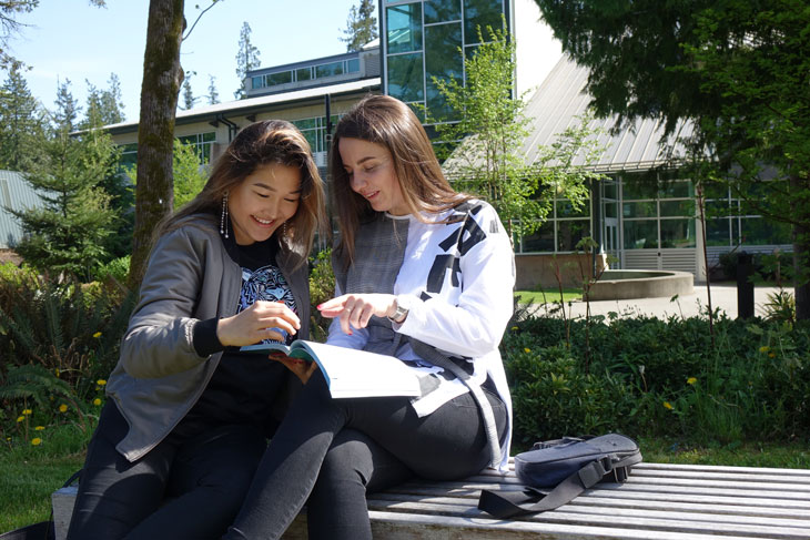 Two female students studying on bench outside Technology Center