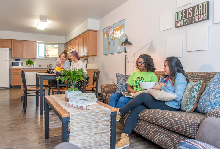 Four students enjoy the remodeled Campus Corner Apartment living area.