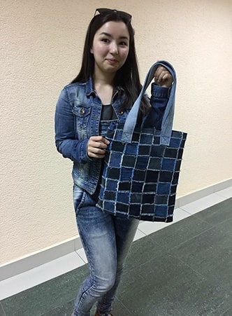 Aiym holding one of the denim bags made from recycled jeans.