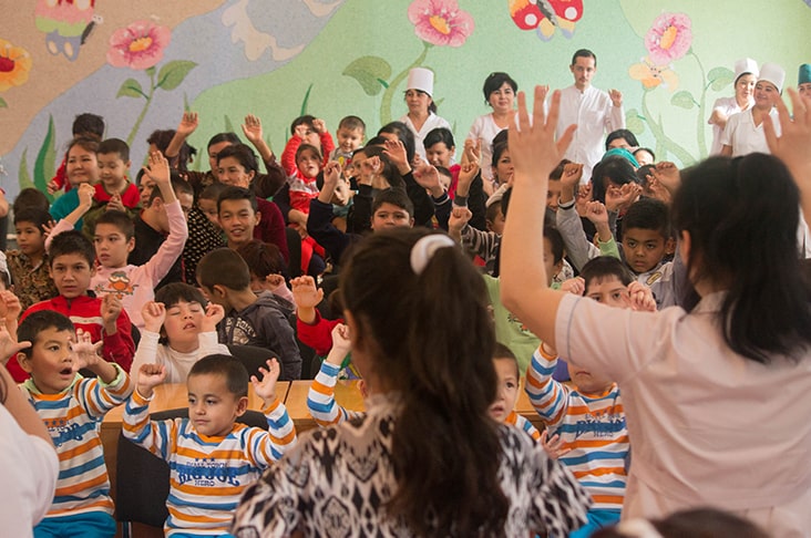 A group of children standing and waving their arms during a performance.
