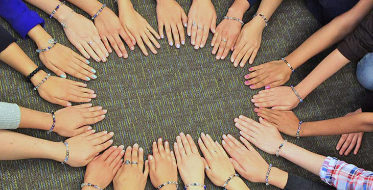 Students put hands in a circle