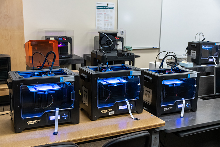 A group of 3D printers in GRC's additive manufacturing lab print PPE