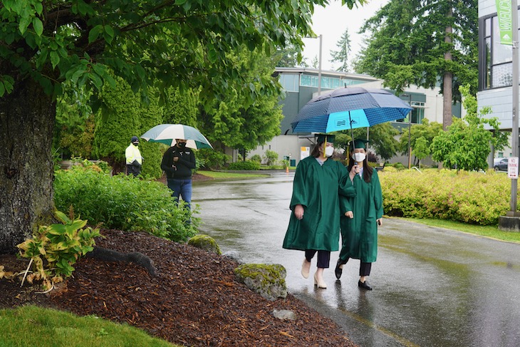 Graduates walk to the stage under umbrella