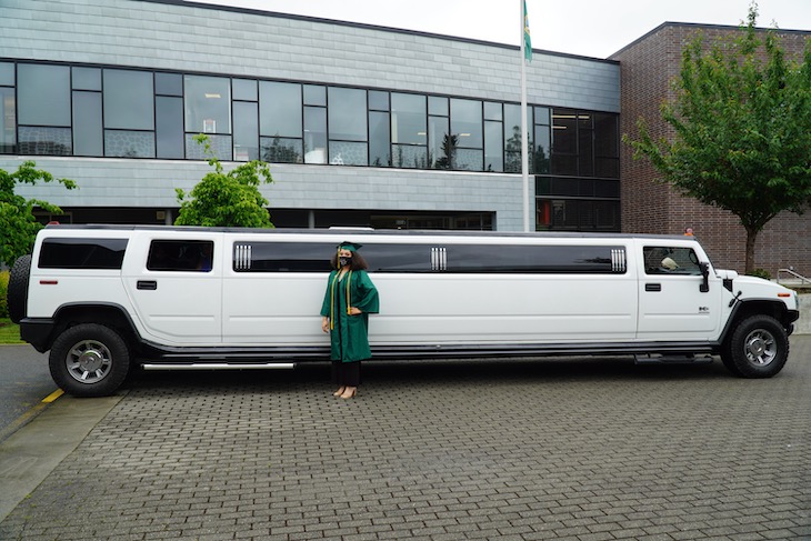 Graduate stands in front of stretch hummer limo