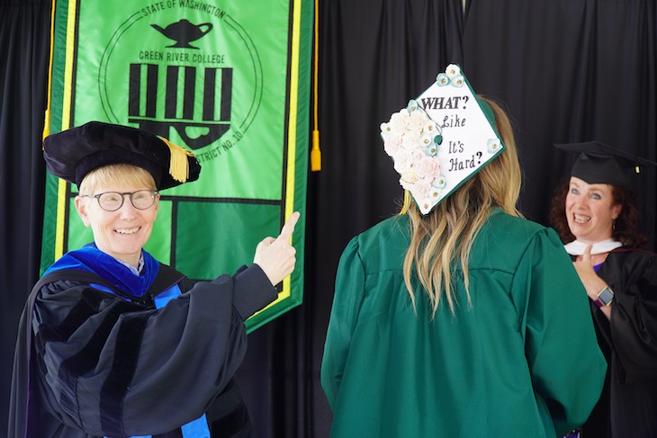 Dr. Johnson points at mortarboard that reads 