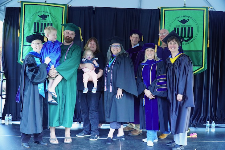 Graduate and family poses on stage