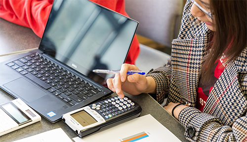 students sitting at a table operating a calculator