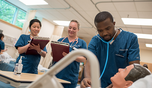 Three students wearing nursing scrubs